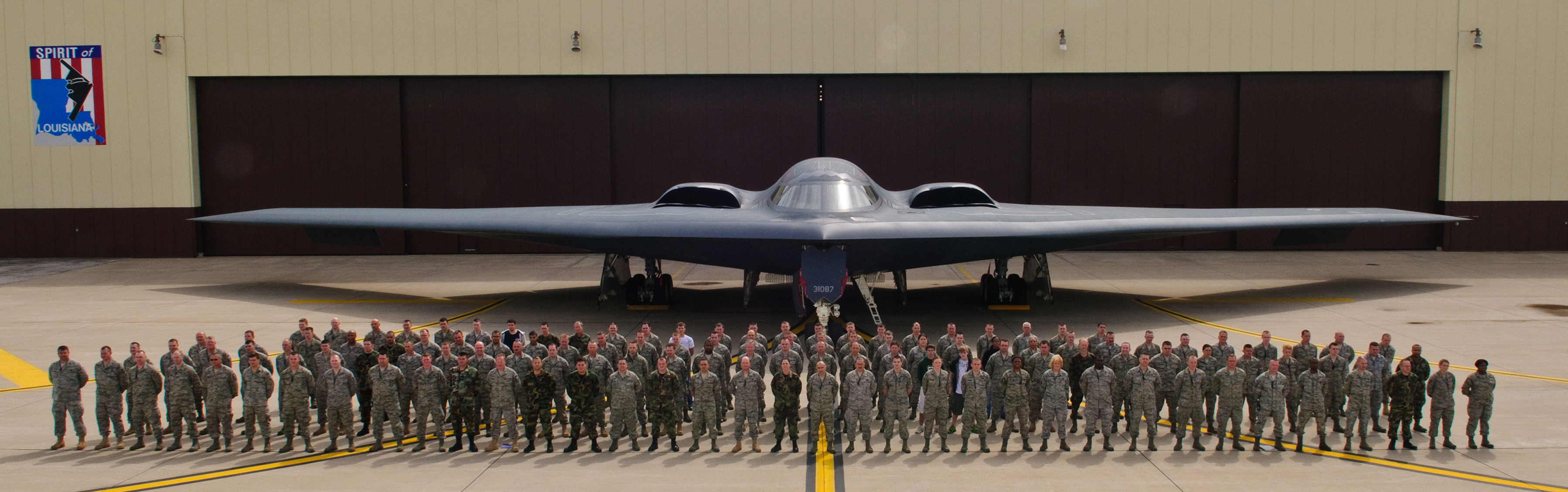 Group photo of approximately 120 Airmen standing in formation in front of a B-2 Spirit stealth bomber.